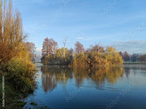 Autumn landscape with lake  - Autumn trees reflected in water. Sunny autumn day in the park