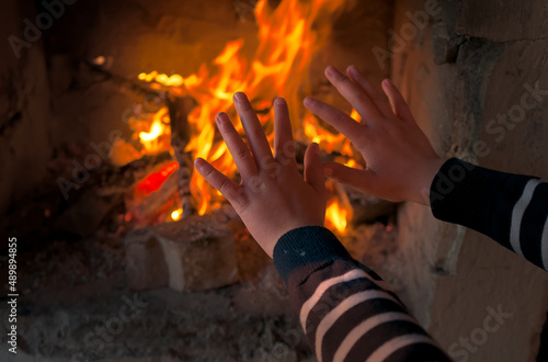 a child is warming their hands by the fire in the fireplace