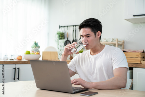 Asian business man drinking miniral water while sit working from home. photo