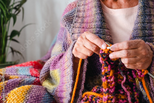 Foto Close up on senior mature woman sitting on sofa at home while knitting
