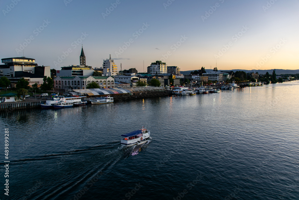 a tourism boat sailing across the Calle-Calle river in Valdivia, southern Chile during sunset