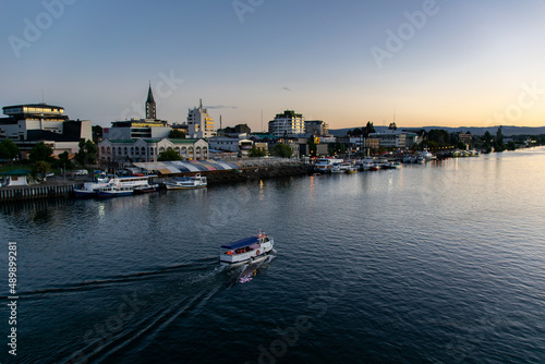 a tourism boat sailing across the Calle-Calle river in Valdivia, southern Chile during sunset photo