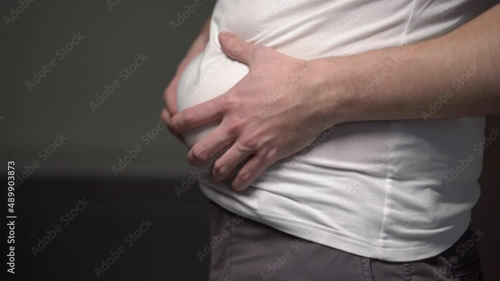 Fat man. Man touches his stomach. Belly, overweight. Oversize person holds skin. Fat man. Man touches his stomach. Belly, overweight. Oversize person holds skin.