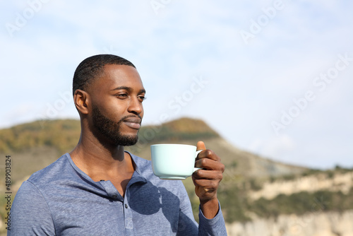Man with black skin drinking and contemplating outdoors