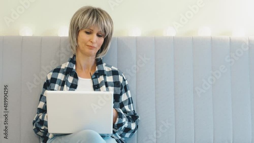 A gray-haired mature woman massages the bridge of her nose, suffers from fatigue after prolonged use of a laptop. The concept of eye strain, a tired middle-aged woman from a long tedious work. photo