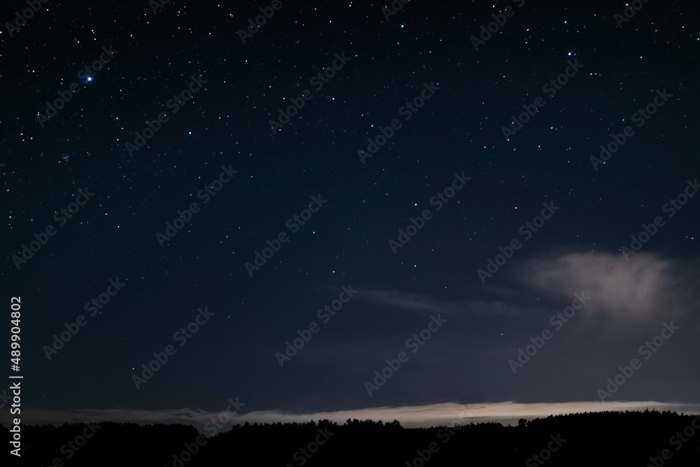 night starry sky over the forest, sky seen from Poland in February, starry sky and black landscape outline night starry sky over the forest, sky seen from Poland in February, starry sky and black landscape outline