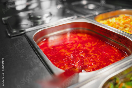 Variety of cooked meals in containers in window of public dining room. Concept of public catering. Delicious borscht. Background.