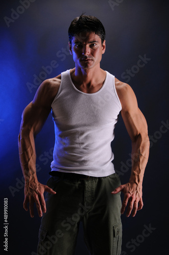 The sexy man is posing in a studio with a dark background. 