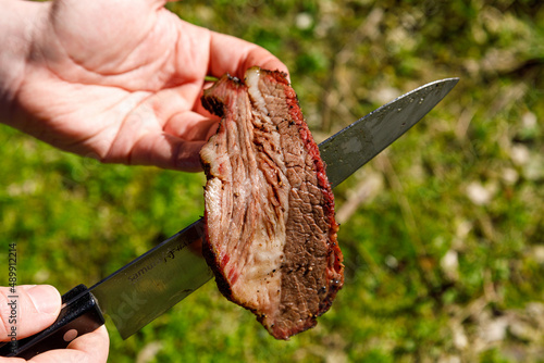 smoked meat on a knife on a natural background