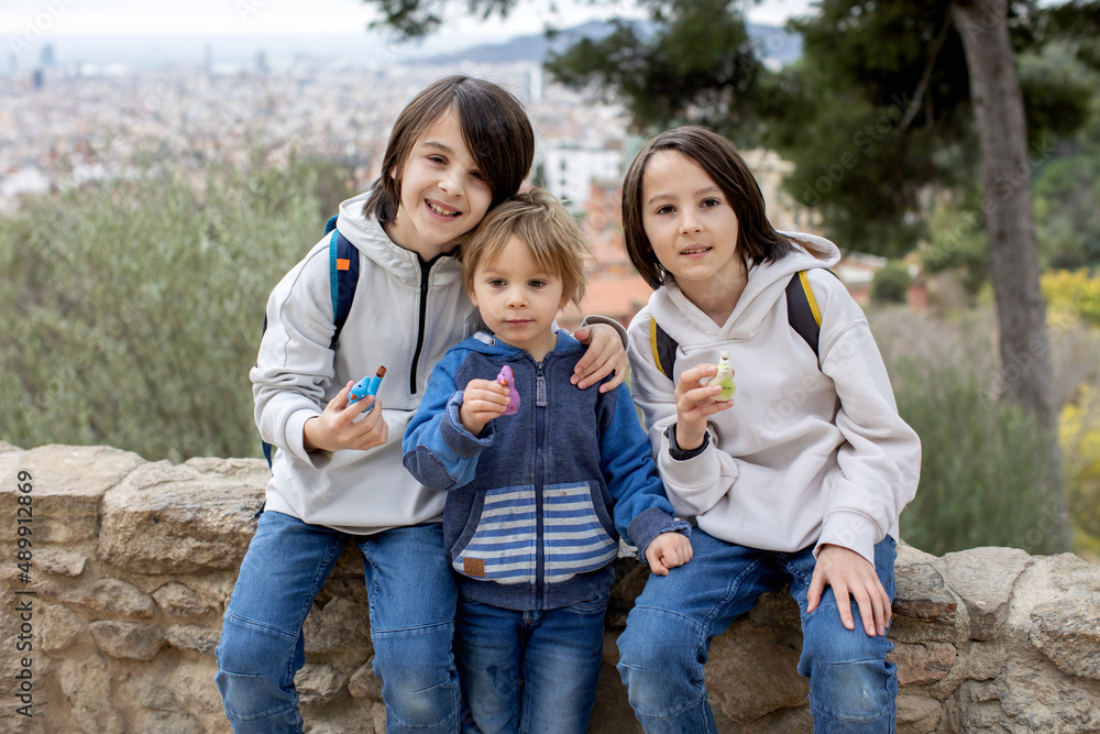 Children, cute boys, playing with ceramic clay whistle in the form of bird, souvenir from park Guell in Barcelona Children, cute boys, playing with ceramic clay whistle in the form of bird, souvenir from park Guell in Barcelona