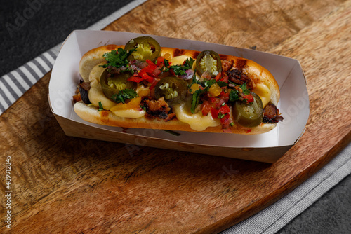 hot dog with jalapeno and vegetables on a dark background