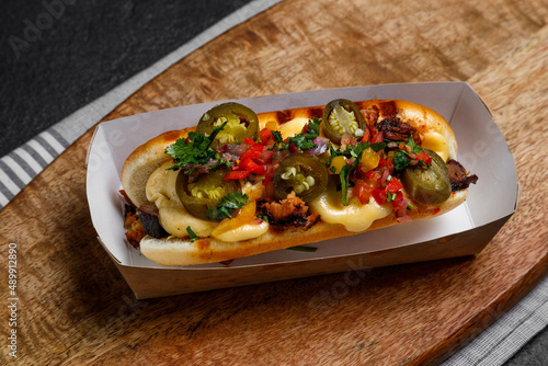 hot dog with jalapeno and vegetables on a dark background