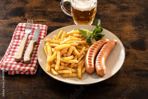 fried with frankfurters in a plate on a table with a beer