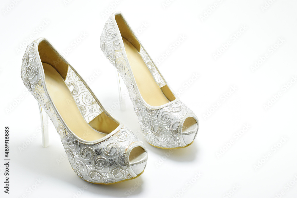 Fotka „Zapatos de tacón para mujer color plateado con diseño. Calzado  formal para fiesta o trabajo sobre un fondo blanco, espacio para texto al  lado derecho, vista superior.“ ze služby Stock