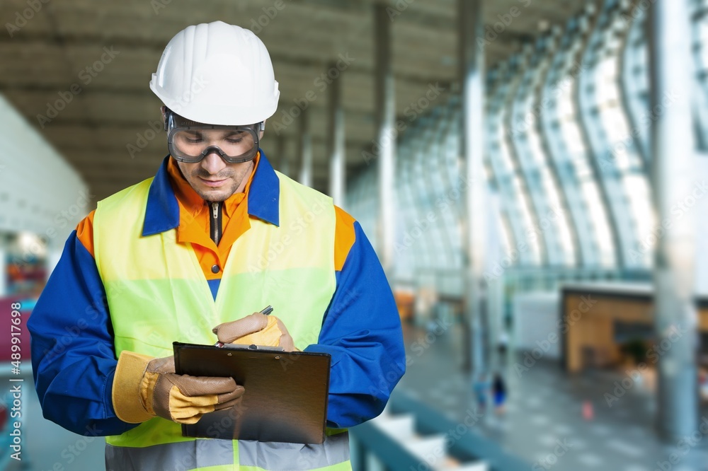 Fototapeta premium Serious and focused architect or engineer working on construction site, checking list