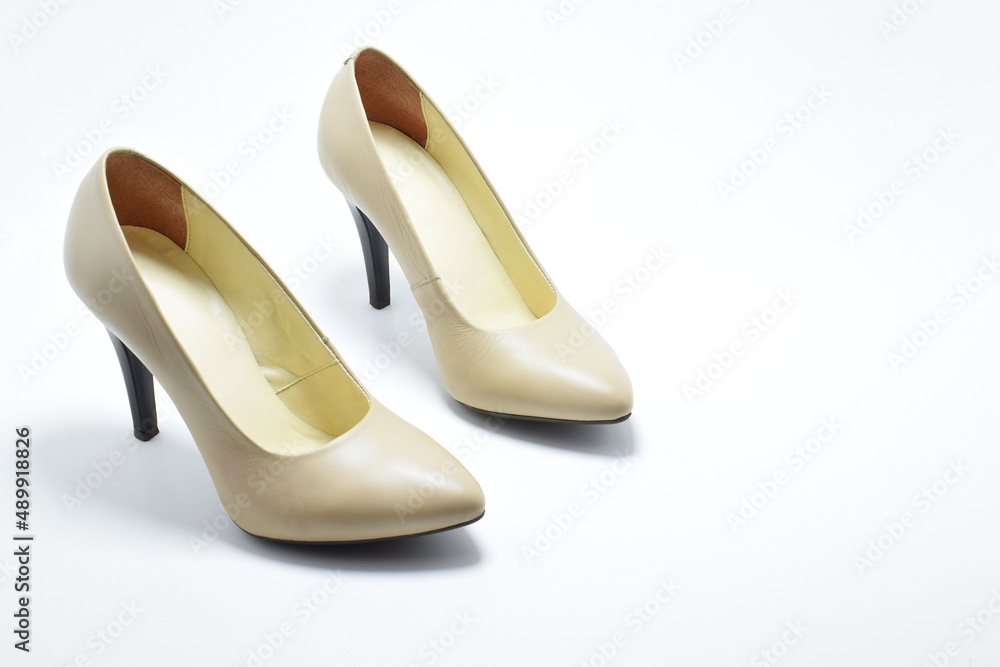 Zapatos de tacón para mujer color beige. Calzado formal para fiesta o trabajo sobre un fondo blanco, espacio para texto al lado derecho, vista superior.