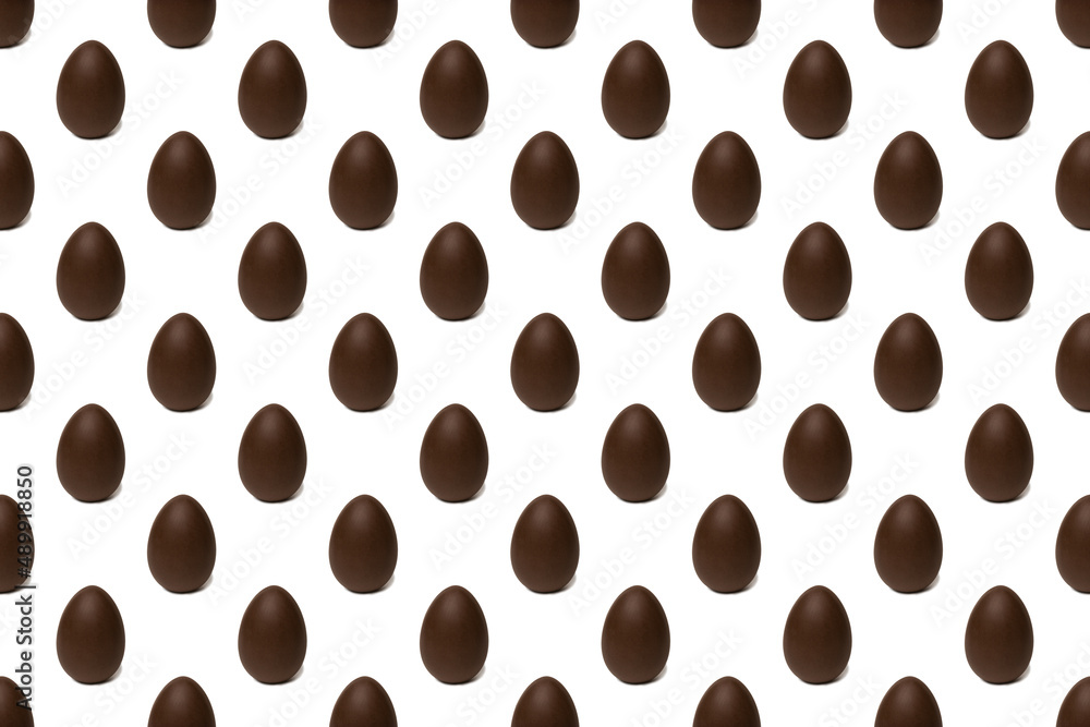 Seamless pattern of whole chocolate Easter eggs on a white background. Easter sweet chocolate background. Seamless pattern of whole chocolate Easter eggs on a white background. Easter sweet chocolate background.