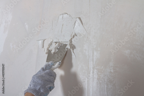 Fotografia Putty the wall in the house with putty using a spatula to level the surface irre