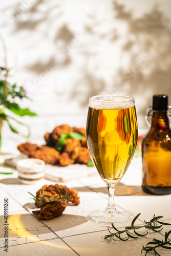 Glass of light beer with chicken wings on white background. Selective focus