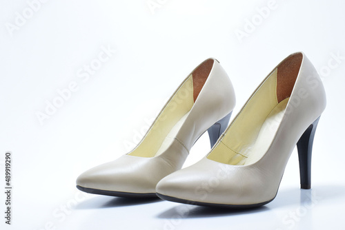 Zapatos de tacón para mujer color beige. Calzado formal para fiesta o trabajo sobre un fondo blanco, espacio para texto al lado izquierdo.