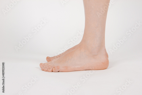 Barefoot and legs isolated on white background. Closeup shot of healthy beautiful female feet. Health and beauty concept. Side view of human foot ream with neutral manicure or pedicure. Sole of foot