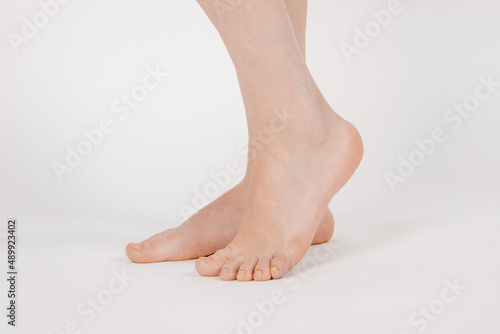 Barefoot and legs isolated on white background. Closeup shot of healthy beautiful female feet. Health and beauty concept. Side view of human foot ream with neutral manicure or pedicure. Sole of foot