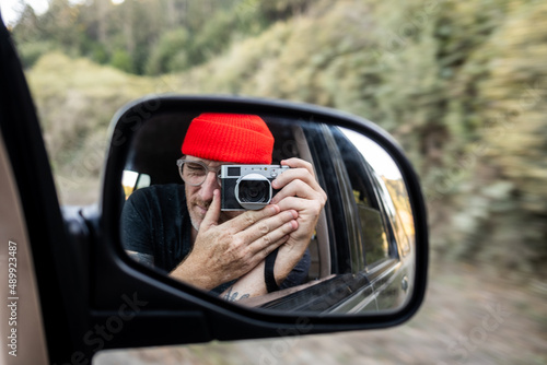 Person taking self portrait in rearview mirror of car while driving