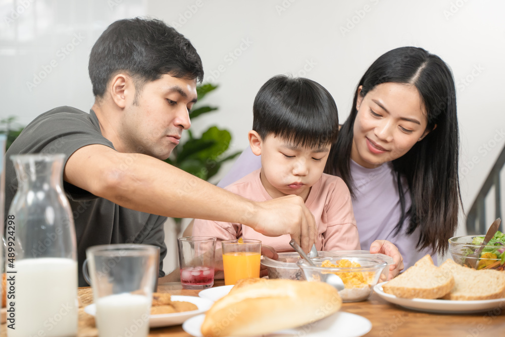 happy family together. Asian parent eating breakfast with little son in the kitchen. happy family together. Asian parent eating breakfast with little son in the kitchen.