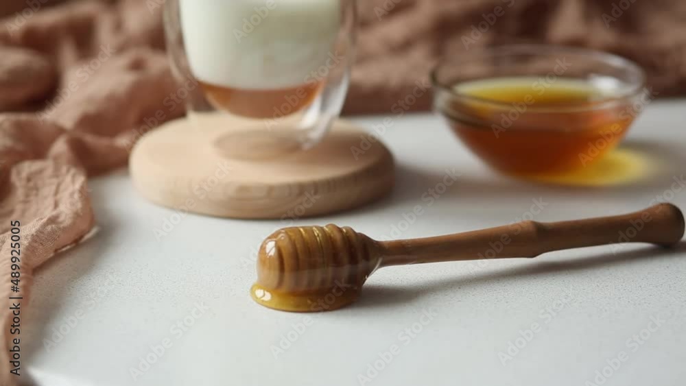 Honey flows from a spoon that lies on the table. Milk and honey. Breakfast, snack. Calming and healthy drink. Honey flows from a spoon that lies on the table. Milk and honey. Breakfast, snack. Calming and healthy drink.