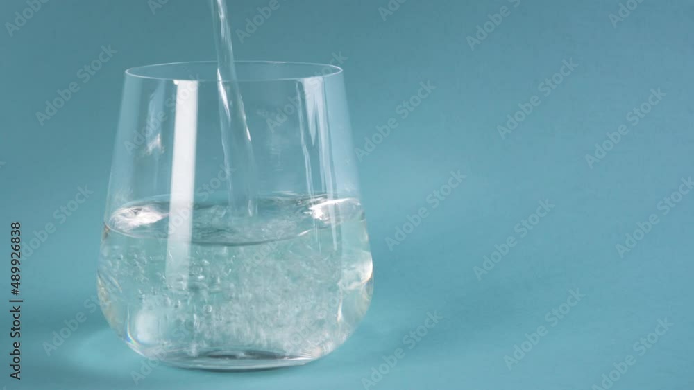 Fresh water is poured into a double walled glass. Blue background. Copy space. Fresh water is poured into a double walled glass. Blue background. Copy space.