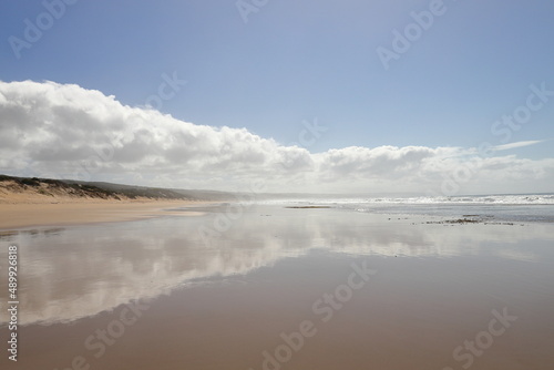 A scenic view on the beach with clouds and reflections.