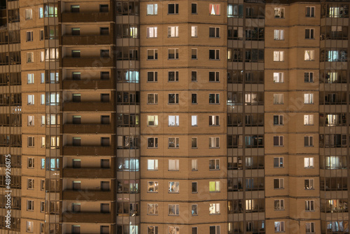 illuminated windows of a brick high-rise apartment building at evening twilight