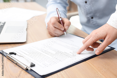 Businesspeople signing contract at wooden table, closeup