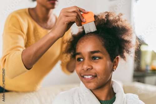 Foto Mother doing head lice cleaning on her daughter curly hair.