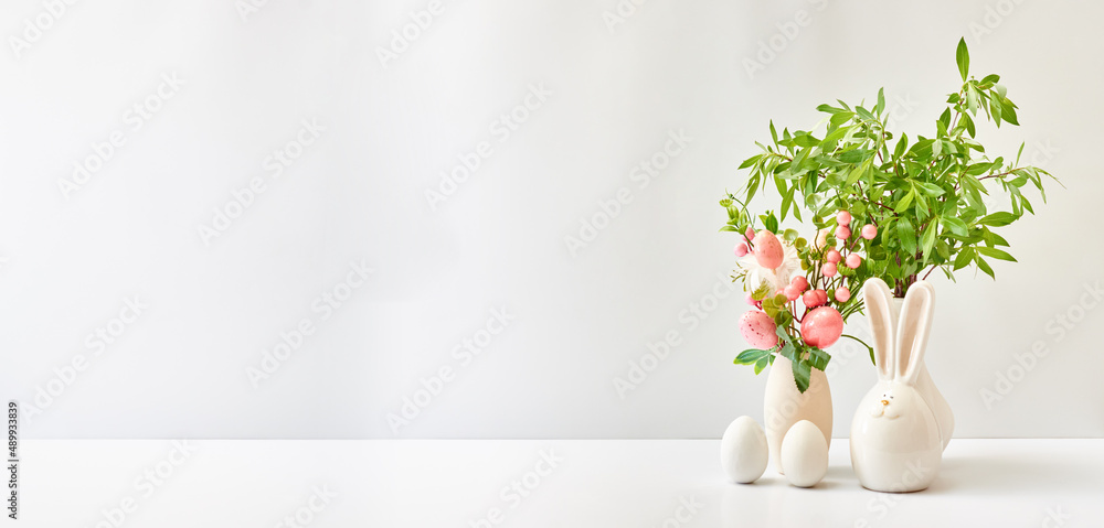 Spring flowers in a vase, easter eggs on a white table. Easter background with copy space