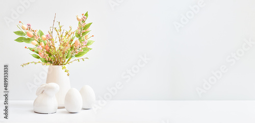 Easter decor in a vase, bunny and eggs on a white table. Easter background with copy space