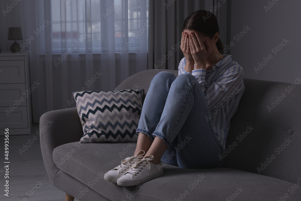 Obraz premium Unhappy young woman crying on sofa at home, space for text. Loneliness concept