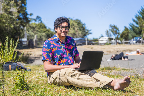 Young latin man doing remote online work from the lake. Teleworking concept. Digital nomad
