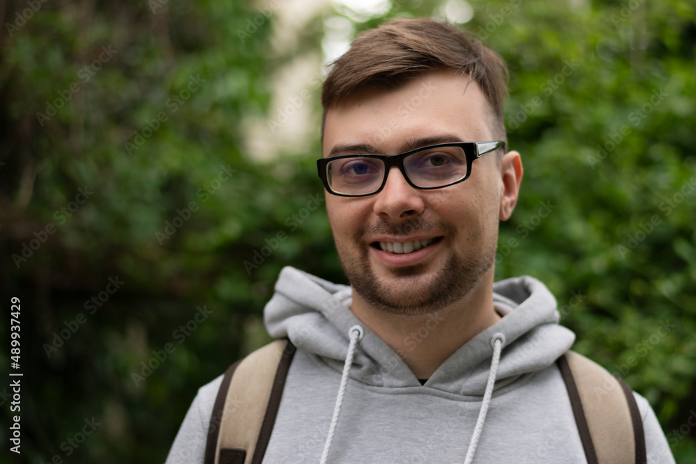 Close-up portrait of a man in a sweatshirt smiling and showing white teeth in the street one Close-up portrait of a man in a sweatshirt smiling and showing white teeth in the street one