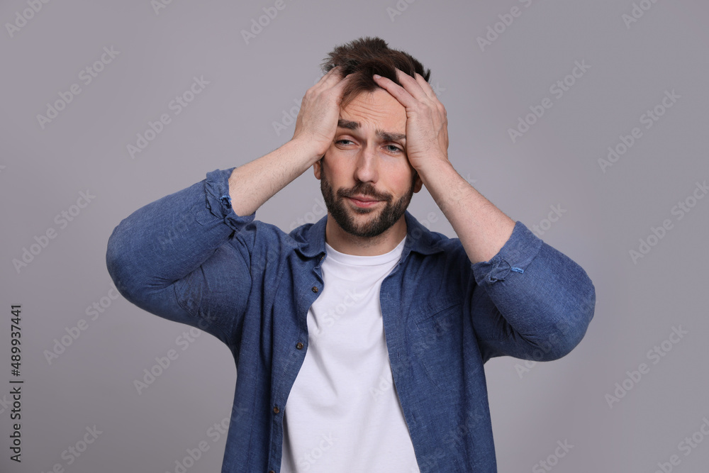 Man suffering from headache on grey background. Cold symptoms Man suffering from headache on grey background. Cold symptoms