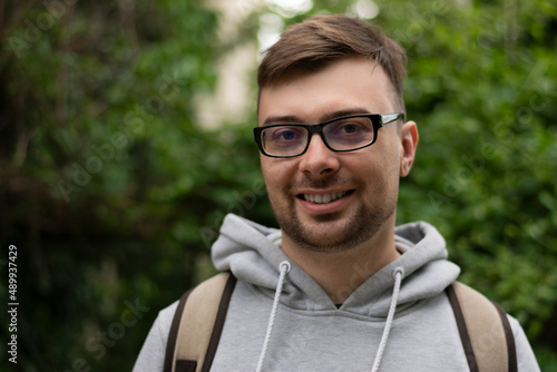 Close-up portrait of a man in a sweatshirt smiling and showing white teeth in the street one