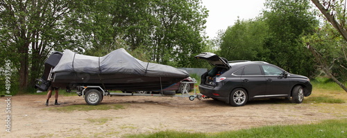 Obraz na płótnie SUV hybrid car with motor boat on single axle boat trailer side view on sandy road. Watercraft active recreation in Europe. w salonie