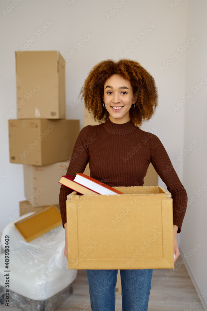 Young woman carrying cardboard box during relocation Young woman carrying cardboard box during relocation