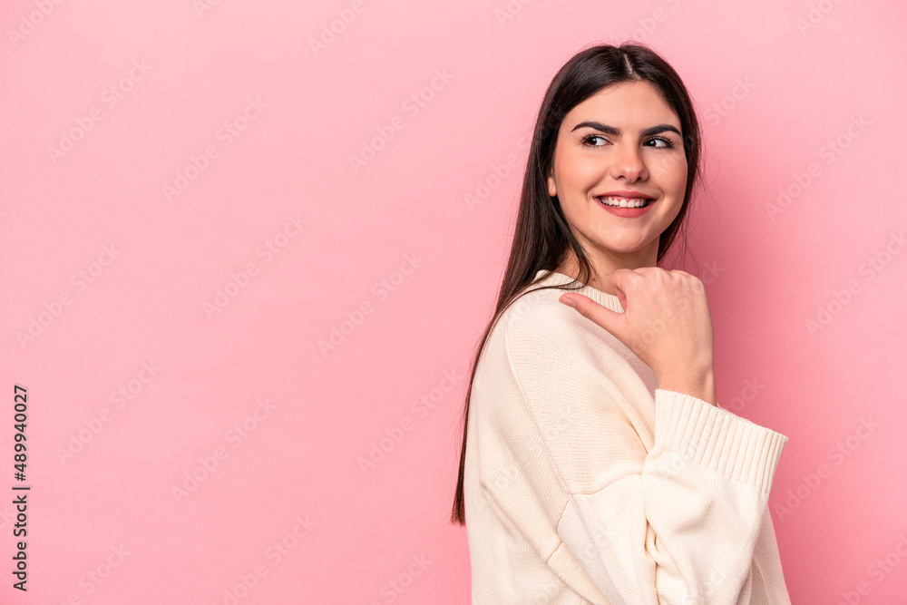 Young caucasian woman isolated on pink background points with thumb finger away, laughing and carefree. Young caucasian woman isolated on pink background points with thumb finger away, laughing and carefree.