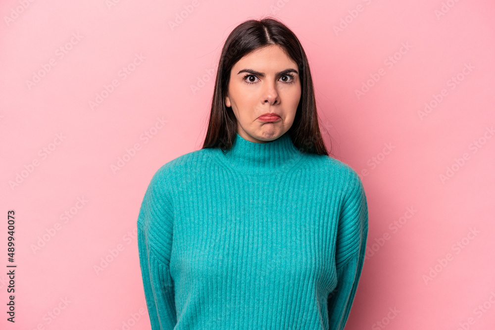 Young caucasian woman isolated on pink background shrugs shoulders and open eyes confused. Young caucasian woman isolated on pink background shrugs shoulders and open eyes confused.
