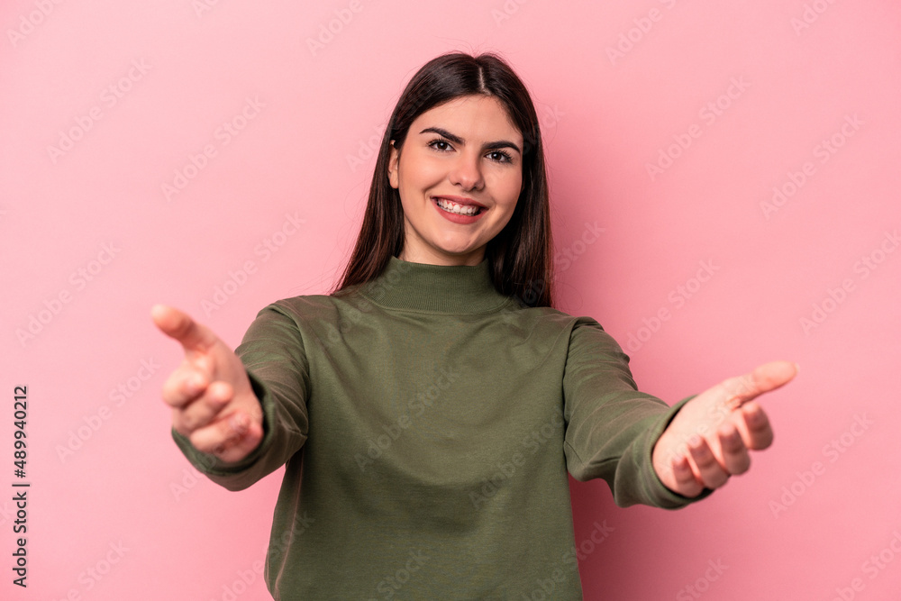 Young caucasian woman isolated on pink background showing a welcome expression. Young caucasian woman isolated on pink background showing a welcome expression.