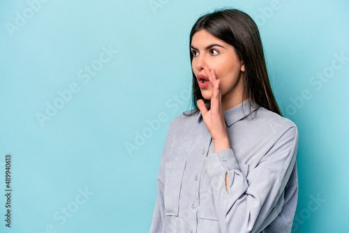 Young caucasian woman isolated on blue background being shocked because of something she has seen.