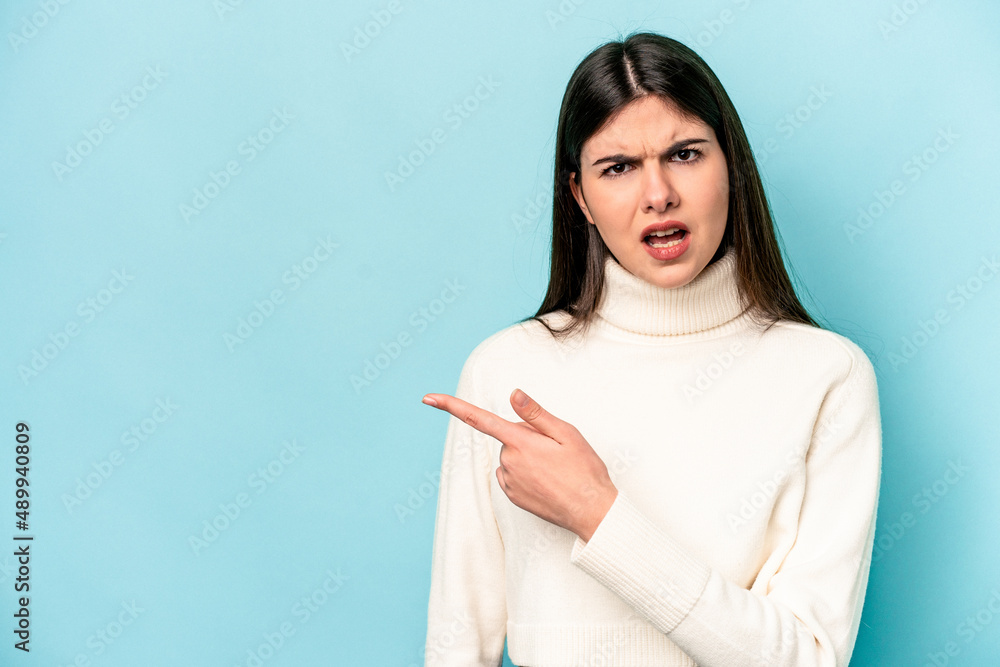 Young caucasian woman isolated on blue background pointing to the side Young caucasian woman isolated on blue background pointing to the side