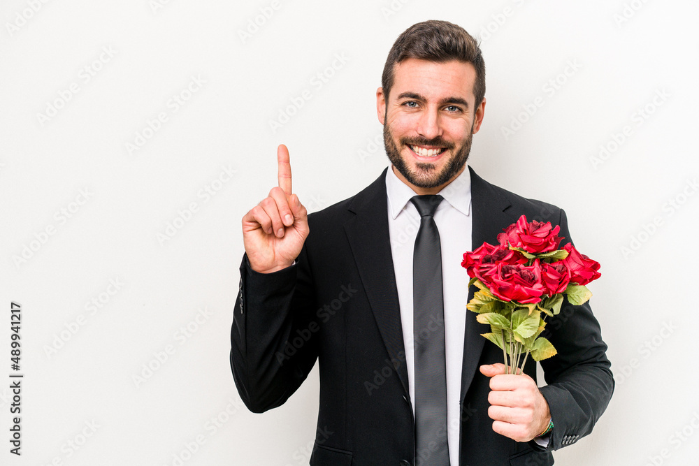 Young caucasian man holding a bouquet of flowers isolated on white background showing number one with finger. Young caucasian man holding a bouquet of flowers isolated on white background showing number one with finger.