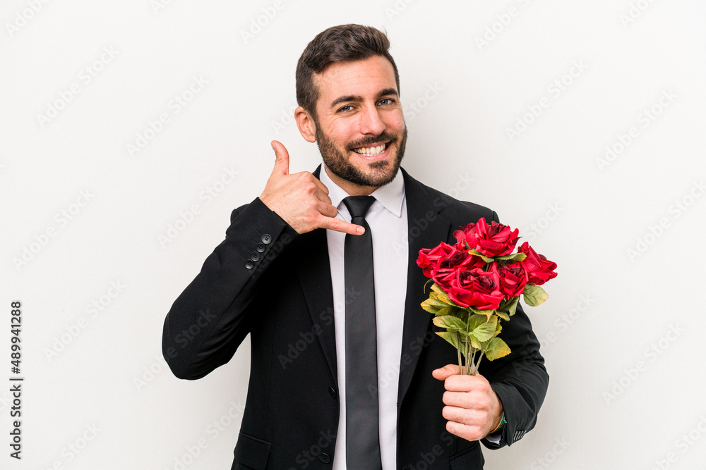 Young caucasian man holding a bouquet of flowers isolated on white background showing a mobile phone call gesture with fingers. Young caucasian man holding a bouquet of flowers isolated on white background showing a mobile phone call gesture with fingers.